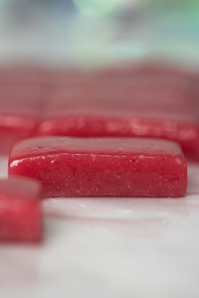 Close-up de pedaço de caramelo macio de framboesa com textura brilhante e cor intensa.