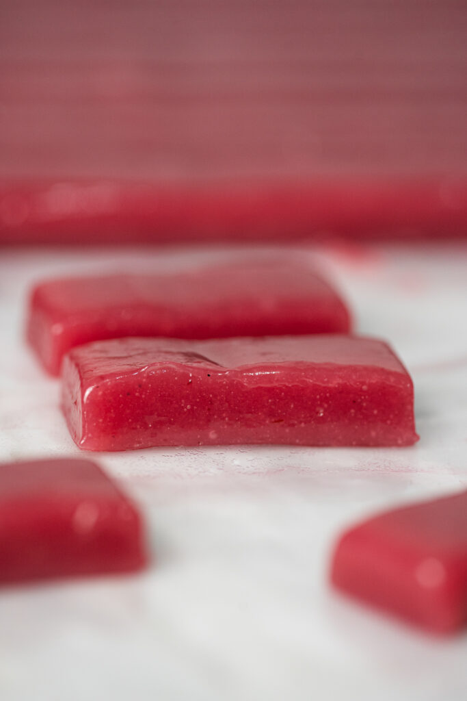 Close-up de pedaço de caramelo macio de framboesa com textura brilhante e cor intensa.