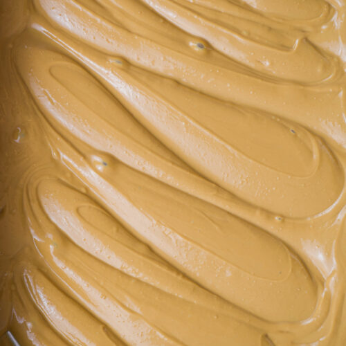 Vista detalhada da superfície do chocolate branco caramelizado, mostrando a textura lisa e o brilho do chocolate com coloração âmbar dourada.