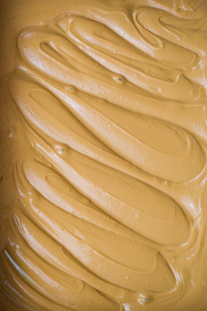 Vista detalhada da superfície do chocolate branco caramelizado, mostrando a textura lisa e o brilho do chocolate com coloração âmbar dourada.
