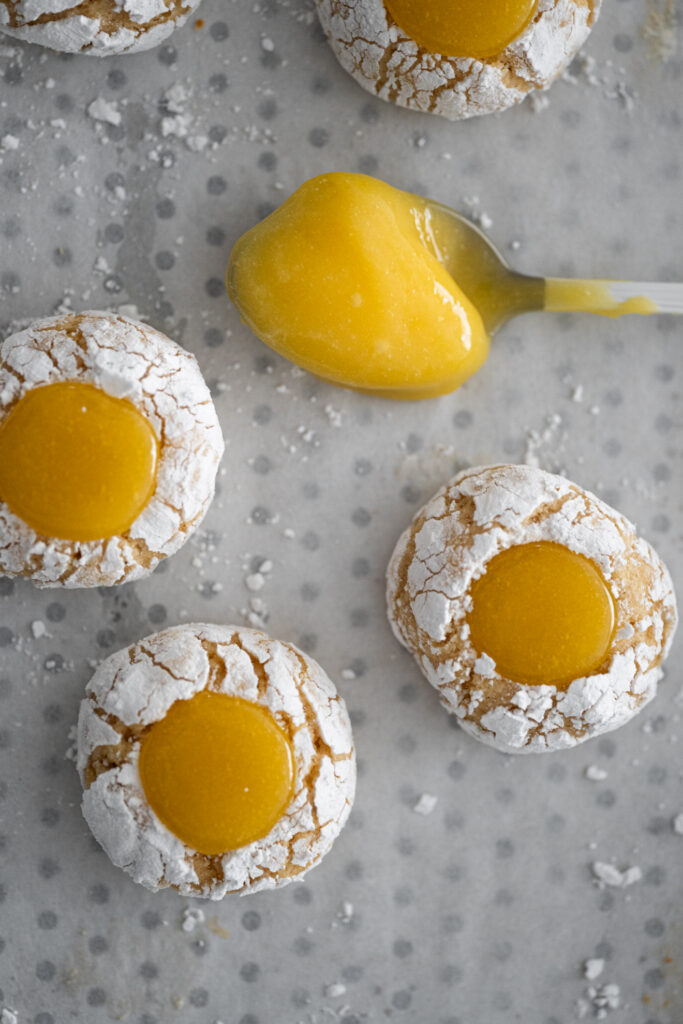 Cookies de limão com lemon curd, craquelados e polvilhados com açúcar de confeiteiro, com recheio cremoso de lemon curd.
